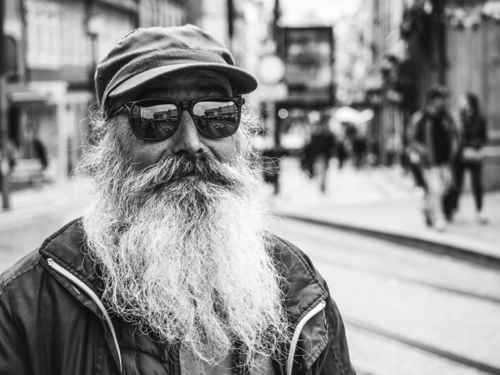 Älterer Mann mit Sonnenbrille, Mütze und weißem Vollbart.